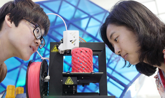 Two visitors watch a working 3D printer on May 23, 2013 at the 16th China Bejing International High-tech Expo in Beijing. [Huang Xiaobing/asianewsphoto]