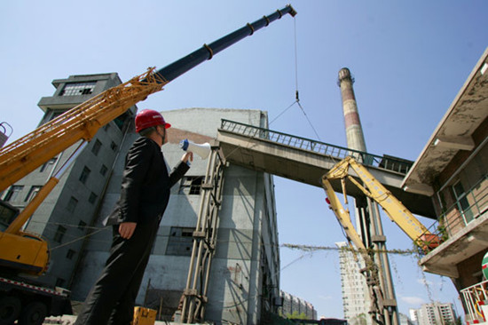 Workers with the Beijing District Heating Group destroy two coal delivery channels with cranes on April 25, marking the beginning of the transformation of energy from coal to gas in the last coal-burning power plant in Beijing. CHENG NING / FOR CHINA DAILY