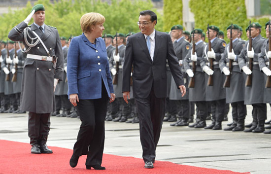 Premier Li Keqiang and German Chancellor Angela Merkel inspect a military honor guard at the chancellery in Berlin, Germany, on Sunday. AFP
