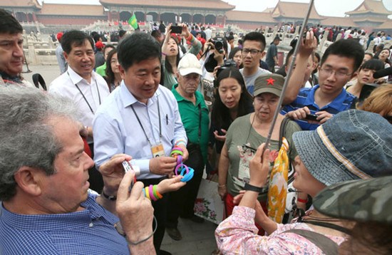 Beijings Palace Museum curator Shan Jixiang and his co-workers give visitors plastic bracelets with Smoke-free Palace Museum printed on them. The Palace Museum announced this month that it will become a no-smoking zone. FU DING / FOR CHINA DAILY