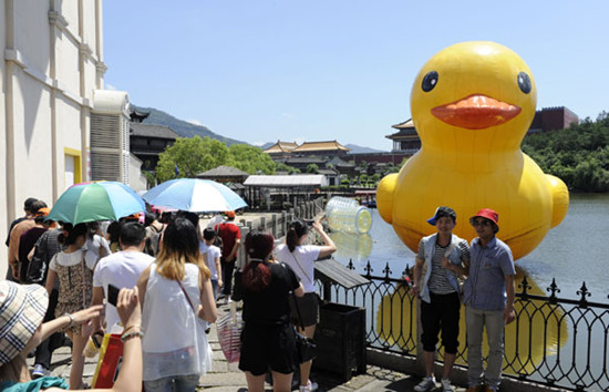 Visitor to Hengdian World Studios in Dongyang, Zhejiang province, take photos of an inflatable rubber duck. [Photo by Bao Kangxuan/Asianewsphoto]