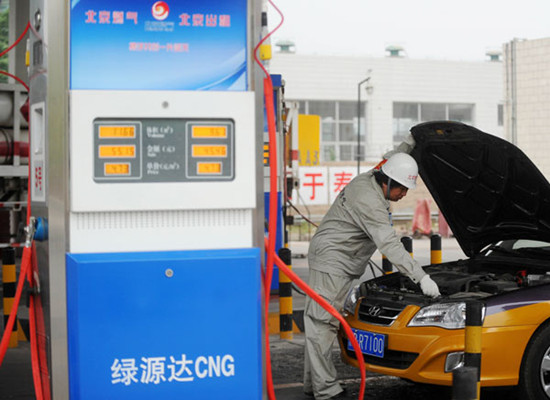 A gas station worker fills a natural gas-fueled taxi in Beijing on Tuesday. Gong Lei / Xinhua