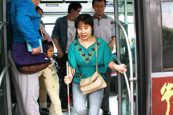 Wang Ying, a blind Beijing resident, exits a bus in the capital on Thursday, the National Eye Health Day. CUI MENG / CHINA DAILY