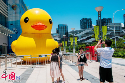 Pedestrians take photos of an inflatable yellow duck, which is believed to be a clone of the one in Hong Kong, at a shopping mall in Shenzhen city, South China's Guangdong province, May 30, 2013. [Photo: China.org.cn]