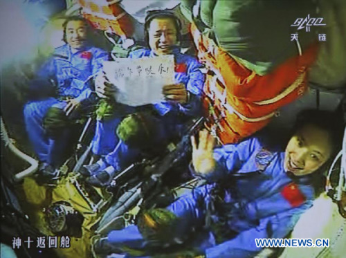 This video grab taken from the screen at the Beijing Aerospace Control Center shows Chinese astronauts on the Shenzhou-10 spacecraft greeting the nation and the Chinese in the global for the Dragon Boat Festival, on June 12, 2013. The words on the paper read Happy Dragon Boat Festival! (Xinhua/Wang Sijang)