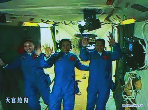 Photo taken on June 13, 2013 shows the screen at the Beijing Aerospace Control Center showing the three Chinese astronauts waving hands at the Tiangong-1 space module. China's Shenzhou-10 manned spacecraft successfully completed an automated docking with the orbiting Tiangong-1 space module at 1:18 p.m. Thursday and the astronauts Nie Haisheng, Zhang Xiaoguang and Wang Yaping opened the hatch of Tiangong-1 at 4:17 p.m. (Xinhua/Wang Yongzhuo)