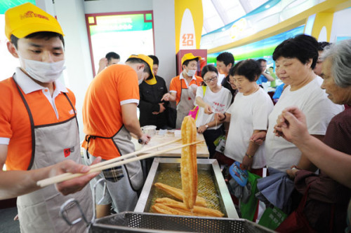 Visitors at a food safety exhibition wait to sample lead-free deep-fried dough sticks in Hangzhou, Zhejiang province, on Friday. The event was meant to improve residents' knowledge of food safety. JU HUANZONG / XINHUA