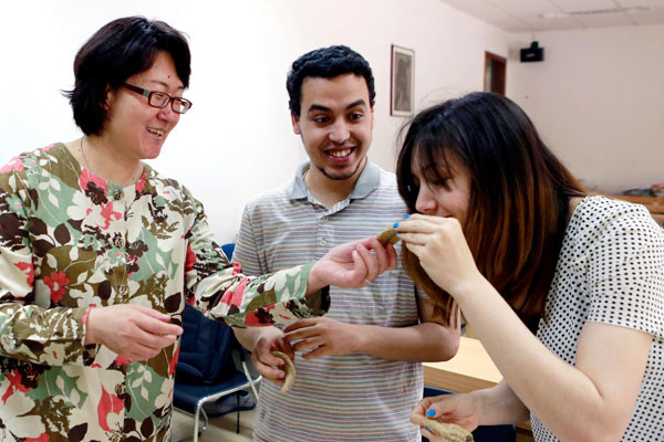 Jia Dexian (left), deputy dean of the International School of Beijing University of Chinese Medicine, teaches students how to distinguish herbs. Feng Yongbin / China Daily