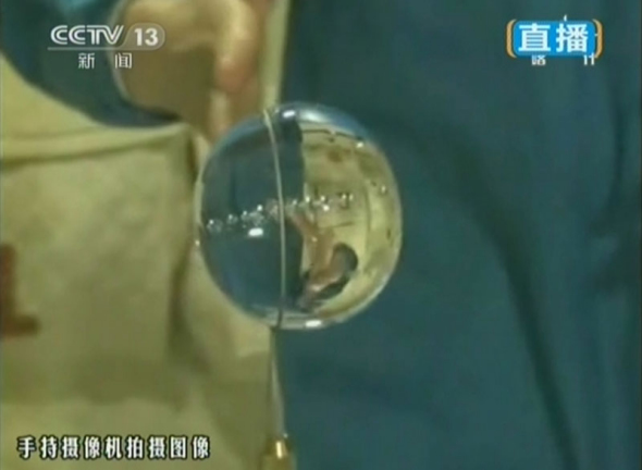 The video grab shows Wang Yaping makes a water film with a water bag and a metal ring. (Photo: CNS) 