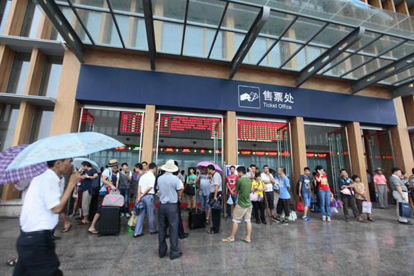 Passengers wait at the ticket office as the trains are suspended as Bebinca, the first tropical storm of the year, made landfall in Hainan on June 22, 2013. [Photo/Xinhua]