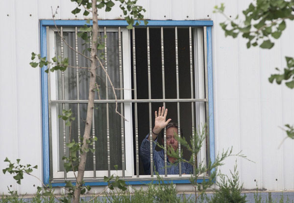 American Chip Starnes, co-owner of Specialty Medical Supplies, waves from a window of an office where he says he's been kidnapped by Chinese workers inside his plant on the outskirts of Beijing, June 24, 2013. [Photo/Xinhua]