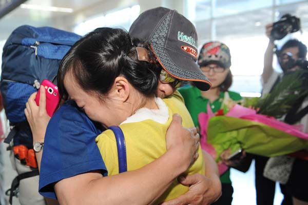 Zhang Jingchuan, a mountaineer who survived a Sunday terrorist attack in Pakistan's northern Gilgit-Baltistan area, hugs his wife on Tuesday at Urumqi International Airport, in the Xinjiang Uygur autonomous region. ZHANG WANDE / FOR CHINA DAILY 
