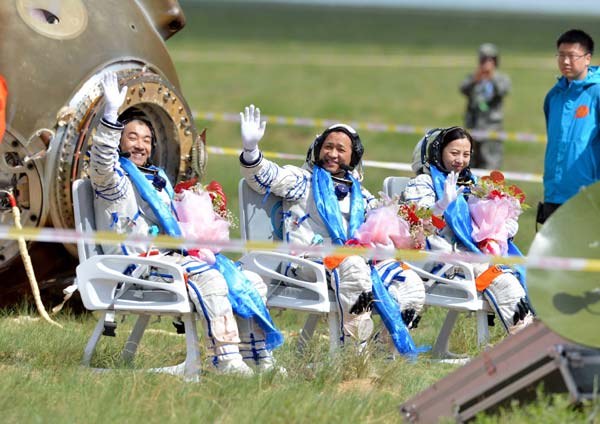 Astronauts Zhang Xiaoguang, Nie Haisheng and Wang Yaping (from left to right) wave after getting out of the re-entry capsule of China's Shenzhou-10 spacecraft following its successful landing at the main landing site in Inner Mongolia autonomous region on June 26, 2013. [Photo/Xinhua]