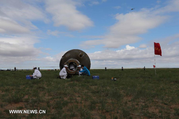 Staff members work at the re-entry capsule of China'sShenzhou-10 spacecraft after its landing at the main landing site in north China's Inner Mongolia Autonomous Region on June 26, 2013. (Xinhua/Wang Jianmin) 