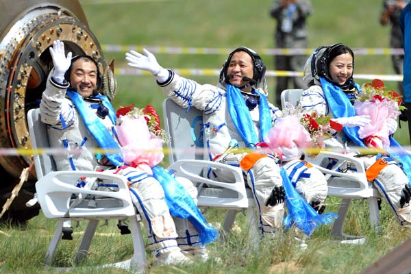 (From left) Astronauts Zhang Xiaoguang, Nie Hai-sheng and Wang Yaping are welcomed after they return from a space mission and land in the Inner Mongolia autonomous region on Wednesday. Wu Yunsheng / For China Daily