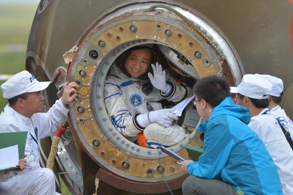 Astronaut Nie Haisheng waves to people outside the Shenzhou X re-entry capsule after a safe landing in the Inner Mongolia autonomous region at about 8 am on Wednesday. WU YUNSHENG / FOR CHINA DAILY
