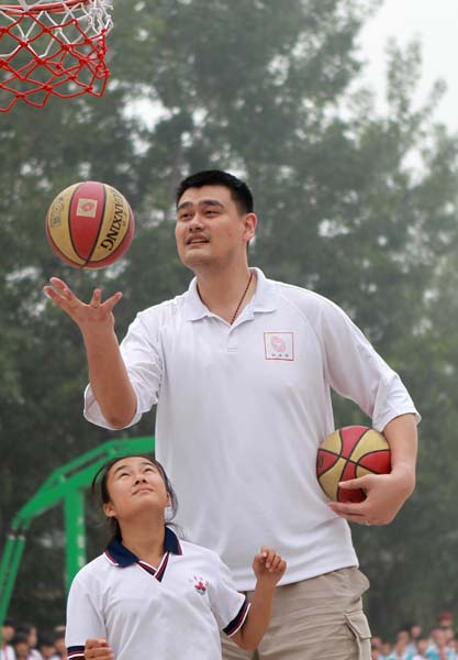 Former NBA star Yao Ming teaches basketball skills to a student from the Huilei School in Beijing's Changping district on Sunday. CUI MENG / CHINA DAILY