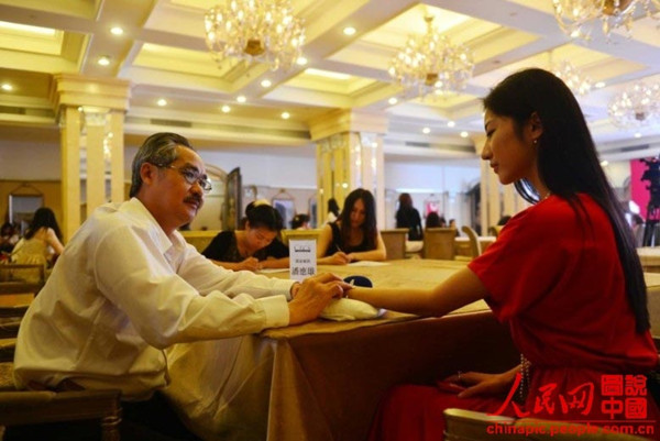 A doctor feels the pulse on a candidates wrist to learn her health condition at the audition for the blind date with rich bachelor held in Beijing on June 30, 2013.  (Photo/ chinapic.people.com.cn)