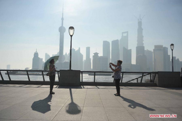 Tourists take photos at the Bund in Shanghai, east China, July 2, 2013. Shanghai meteorological bureau issued an orange-coded heat alert Tuesday, as parts of the city have been under the highest temperature of 38 degrees Celsius. (Xinhua/Liu Xiaojing)