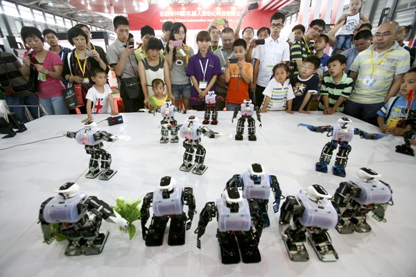 Visitors are attracted to a performance by intelligent robots during the four-day 2013 China International Robot Show, which- opened on Tuesday in Shanghai.