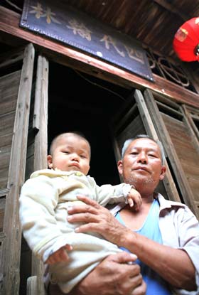 Zhou Yeji and his grandson pose at the gate of his old house, where four generations of excellent scholars lived in the Qing Dynasty (1644-1911). Huo Yan / China Daily 