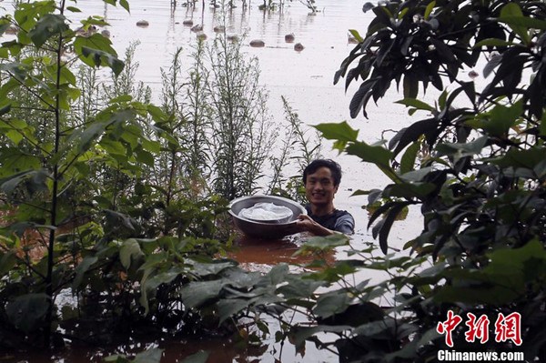 A man in Chongqing swam across a flooded river to fetch hot food for his pregnant wife trapped by rising floodwater. (Photo: CFP)