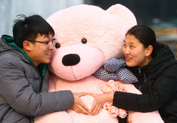 Kang Zhiming and his girlfriend Meng Xue have fun with a giant toy bear at Oriental Plaza in Beijing's Wangfujing Street. Zou Hong / China Daily