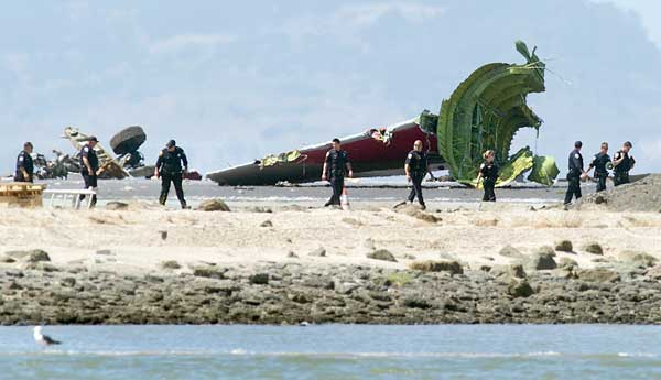Investigators pass the detached tail and landing gear of Asiana Flight 214 after the crash at San Francisco International Airport on Saturday. Noah Berger /AP Photo 