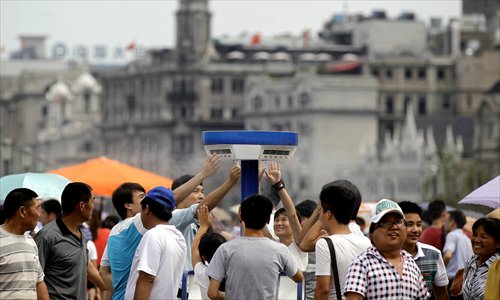 Visitors to the Bund crowd around a cooling device to get a refreshing spray of water Sunday, when the high temperature exceeded 35 C. The Bund's six cooling devices start running when the temperature reaches 32 C. Photo: Yang Hui/GT 
