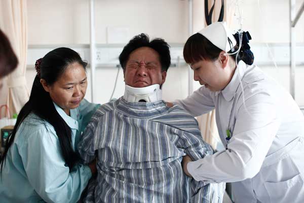Wang Jianzhong, who caught a boy who fell from a buildings fourth floor on July 1, thus saving his life, receives treatment at a hospital in Shanghai. Yang Yi / for China Daily 