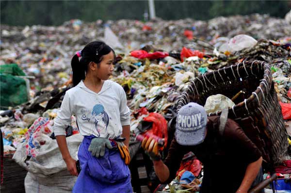 A girl works with her family at a dump in Guiyang, the capital of Guizhou province. Lin Jian / for China Daily