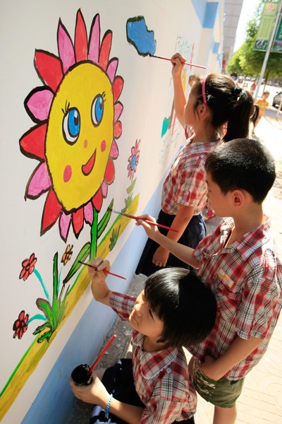 Students at a primary school in Hengyang, Hunan province, decorate a wall surrounding a construction site for their summer vacation homework assignment. Peng Bin / for China Daily