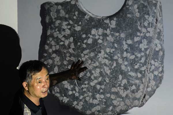 Cao Jinyan, an archaeologist at Zhejiang University, introduces written characters that date back 5,000 years on a stone axe at a seminar in Hangzhou, Zhejiang province, on Tuesday. The characters, believed to be the earliest ever discovered, are engraved on stone axes that were excavated from the ruins of the Zhuangqiao tomb in Qunfeng village of Lindai township, Pinghu city. HAN CHUANHAO / XINHUA