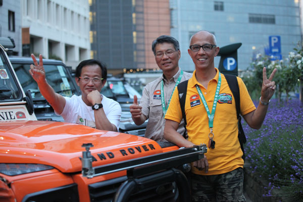 Eric Ma (left), Tommy Choy (middle) and Michael Lee, all from Hong Kong Land Rover Club, organizers of Hong Kong Land Rover fans' ongoing 33,000 kilometers global expedition, pose before the hotel parking in Brussels in Brussels over the weekend. [Photo by Fu Jing/China Daily]