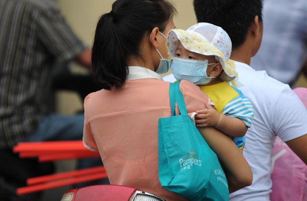 A woman and her child protect themselves from pollution in Zhengzhou, Henan province, in June. Deng Yinming / for China Daily