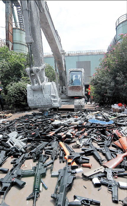 An excavator runs over illegal weapons and knives at a steel plant in Shanghai. More than 300 guns and 340 imitation guns as well as 2,200 illegal knives were destroyed yesterday in a public demonstration of the city's efforts to crack down on illegal weapons. The metal parts were melted down and will be reused, while nonmetallic parts were crushed, police said. Most of the guns and bullets were handed in by individuals and firms. There have been 18 gun-related crimes this year and 26 people suspected of crimes involving illegal weapons have been arrested.