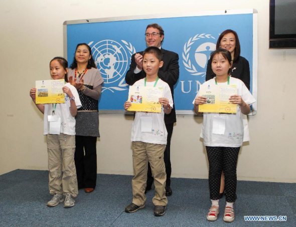 UN Environment Program (UNEP) Executive Director Achim Steiner (C back) poses with young Chinese painters at the UNEP headquarters in Nairobi, capital of Kenya, on July 16, 2013. The 17 winners of the annual Chinese children painting competition were unveiled on Tuesday by the UN Environment Program (UNEP) in Nairobi. An estimated 630,000 school children participated in the 2013 Chinese Children's painting competition organized by UNEP and the Luo Hong Foundation to capture the vision of a water scarce planet. (Xinhua/Meng Chenguang)