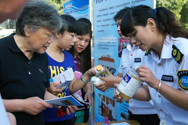 Officials from the food and drug administration and other local authorities in Xingtai, Hebei province, explain food and drug security to locals in June. Chen Kejia for China Daily