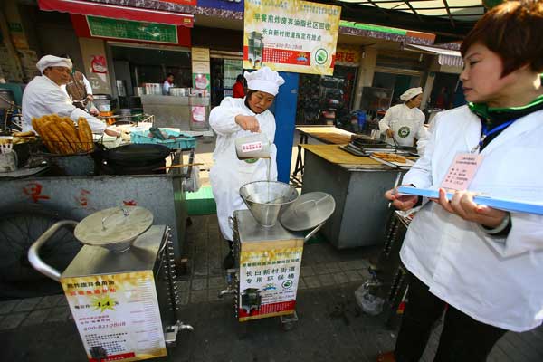 A community worker (center) in Shanghai recycles used cooking oil on March 6. Public concern over illegal oil pushed Chinese scientists to find ways to fight against gutter oil. wu kai / for China Daily
