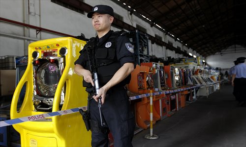 A police officer guards some of the more than 4,000 seized gambling machines that were destroyed Thursday in Baoshan district. Photo: Yang Hui/GT 