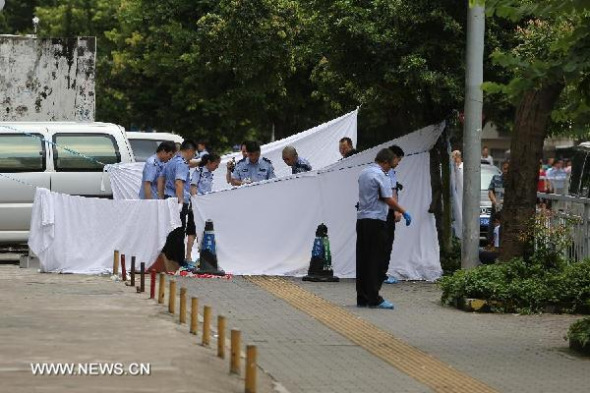 Policemen make an investment at the accident site where a man attacking people with a knife in Luohu District of Shenzhen City, south China's Guangdong Province, July 29, 2013. Three people died and another five were injured in a knife attack that occurred Monday in the city of Shenzhen. Police later detained the man and rushed the injured to the hospital. The man, surnamed He, was also sent to the hospital for treatment, as he injured himself during the attack. Initial investigation showed that the man had a history of mental illness. (Xinhua/Yu Haihong) 