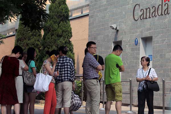 People line up in front of the Canadian embassy in Beijing to apply for visas on Wednesday. Insiders said a strike by foreign service officers in Canada will have some effect on the processing of visas. [Wang Jing / China Daily]