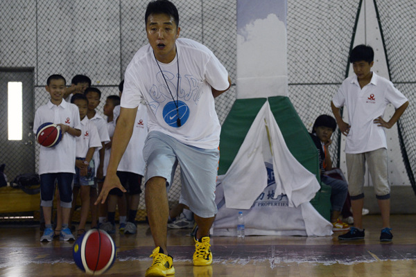 Former professional basketball player Yan Yufeng demonstrates moves for children on a six-day trip to Beijing supported by the China Red Ribbon Foundation on July 24. Many of the 103 youngsters are HIV-positive. Wei Xiaohao / China Daily
