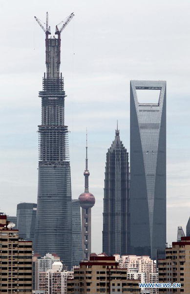 Photo taken on Aug. 3, 2013 shows the Shanghai Tower (L) under construction in Shanghai, east China. A topping-out ceremony was held Saturday for the Shanghai Tower, China's tallest building, which remains under construction until its scheduled completion in 2015. The 125-story building, now 580 meters high, is scheduled to reach a final height of 632 meters upon completion in 2015. (Xinhua/Pei Xin)