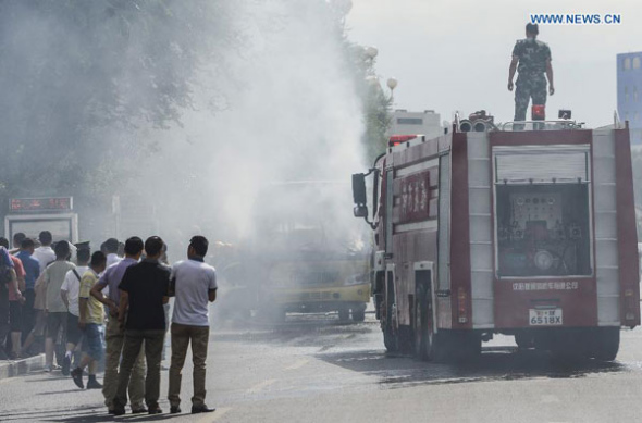 Firefighters work at the bus fire scene in Urumqi, capital of northwest China's Xinjiang Uygur Autonomous Region, Aug. 5, 2013. A bus bursted into flames on Guangming Road in Urumqi on Monday, causing one dead and six injured. (Xinhua/Zhao Ge)