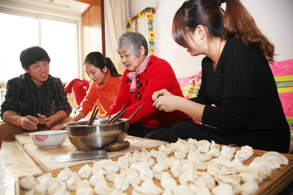 Student volunteers in Qingdao, Shandong province, make dumplings at the home of an elderly woman surnamed Gao who lost her son in an accident. They visit her on a regular basis to help her with housework and chat with her.Liu Jishun / for CHINA DAILY