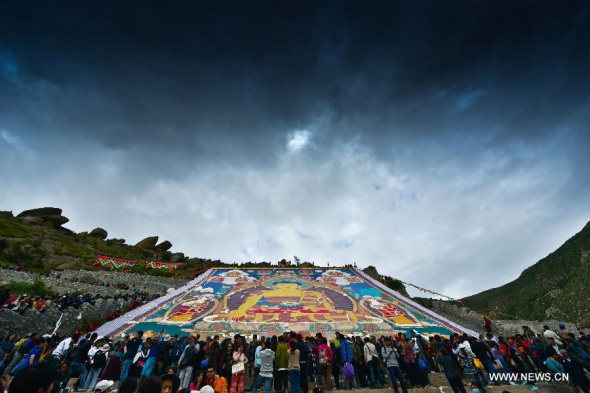 Buddhists and tourists participate in the sacred sunning of the Buddha ceremony to mark the start of the annual Shoton festival at the Zhaibung (Drepung) Monastery in Lhasa, capital of southwest China's Tibet Autonomous Region, Aug. 6, 2013. The Shoton festival dates back to the 11th century and was originally a religious occasion, when local people offered yogurt to monks who had finished their meditation retreats. Since the 17th century, the festival has become a celebration featuring both religious rituals and civil entertainment. It is now considered as one of the most important festivals on the Tibetan calendar. (Xinhua/Purbu Zhaxi)  