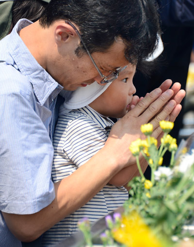 A father helps his son pray for victims of the 1945 atomic bombing at the Peace Memoral Park in Hiroshima. Toru Yamanaka / Agence France-Presse