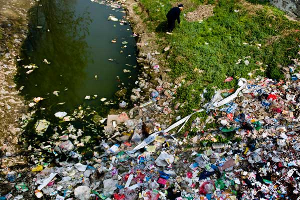 Garbage piles up on the bank of a polluted feeder of the Shaying River, the biggest distributary of the Huaihe River, in Shenqiu, Henan province. Residents of several villages along the Shaying River have been ravaged by cancer as a result of water pollution. [Sun Junbin / for China Daily]