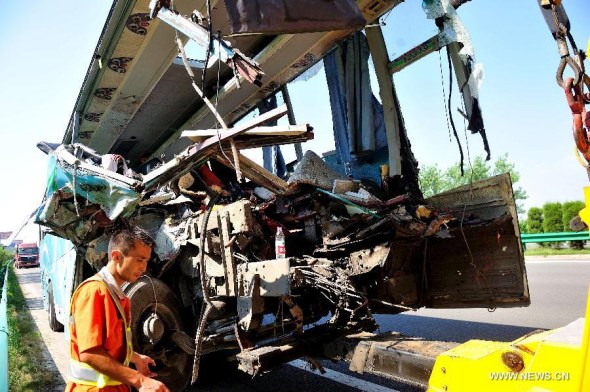 A damaged coach is pulled out of the accident site of collision on the Hehuifu Expressway in east China's Anhui Province, Aug. 9, 2013. At least 10 people were dead and 34 others injured after the coach ran into the rear of a heavy-loaded truck Friday morning. (Xinhua)  